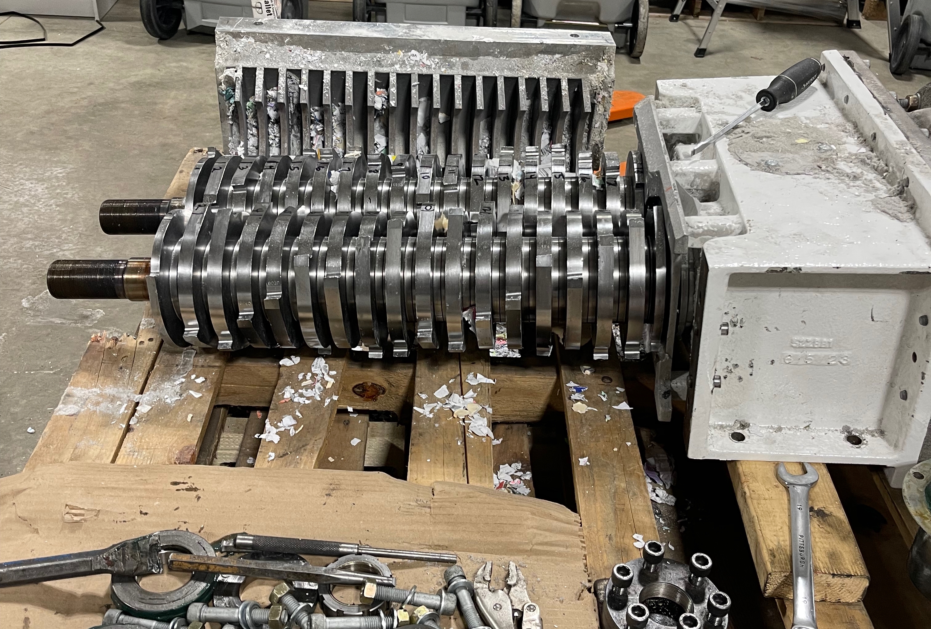 Disassembled shredder rotor and parts on workbench